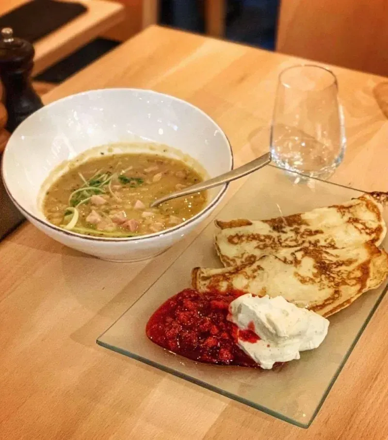 Ärtsoppa serverad med pannkakor, sylt och grädde